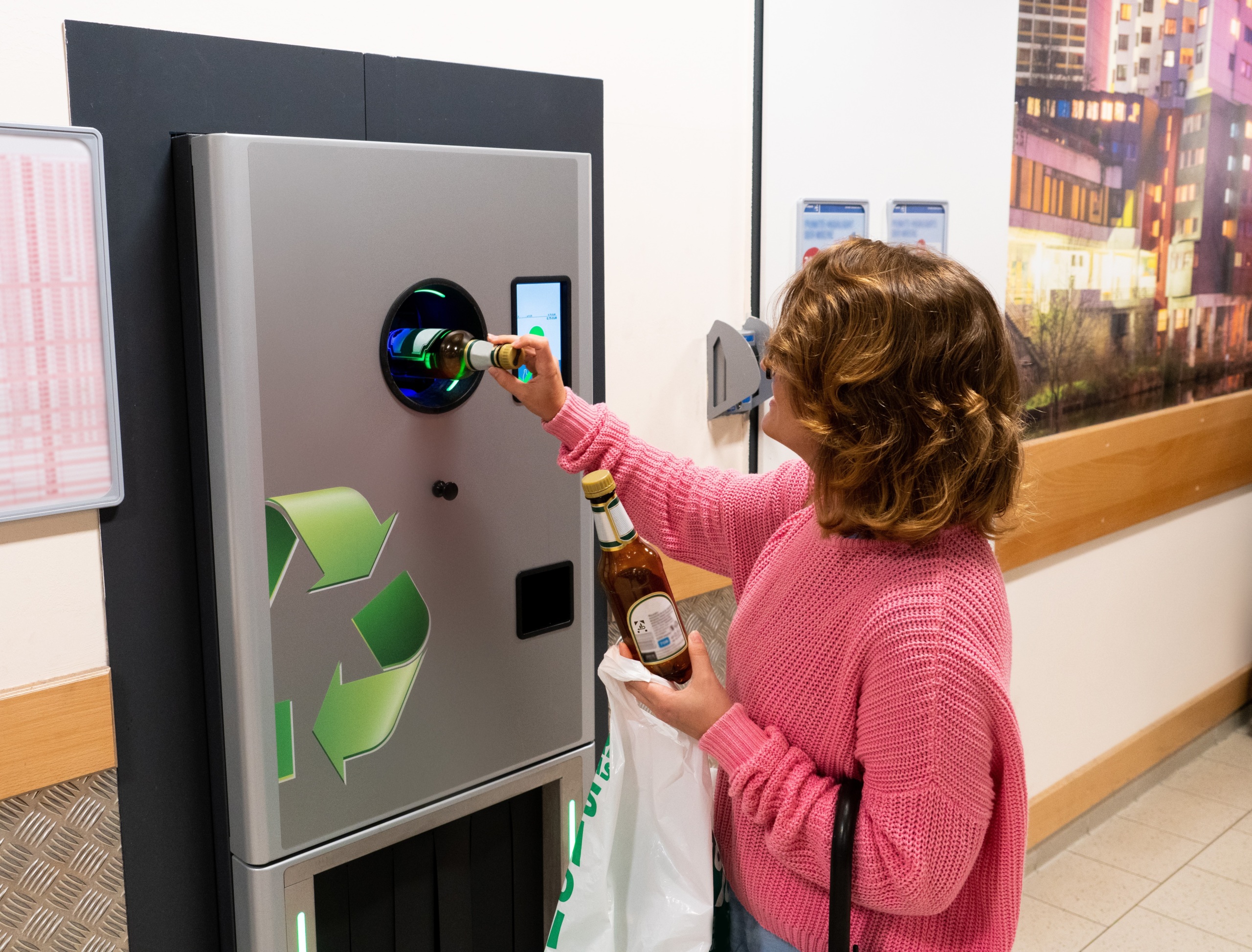 A woman inserts glass bottles into a machine for recycling.