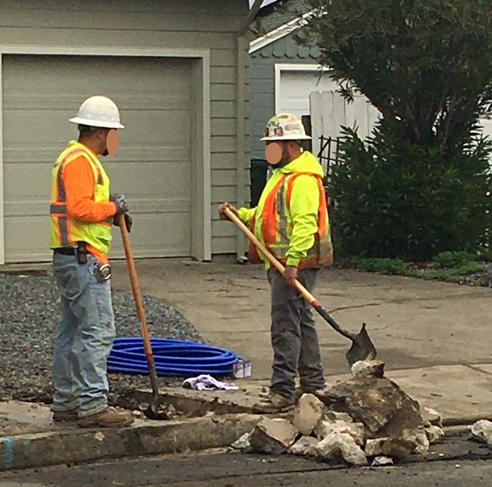 workers with shovels digging out concrete from sidewalk