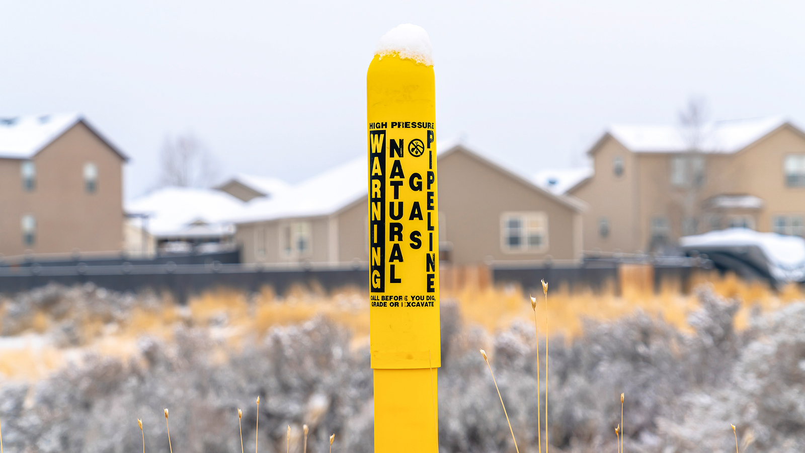 Pole marker with warning sign for natural gas pipeline buried underground