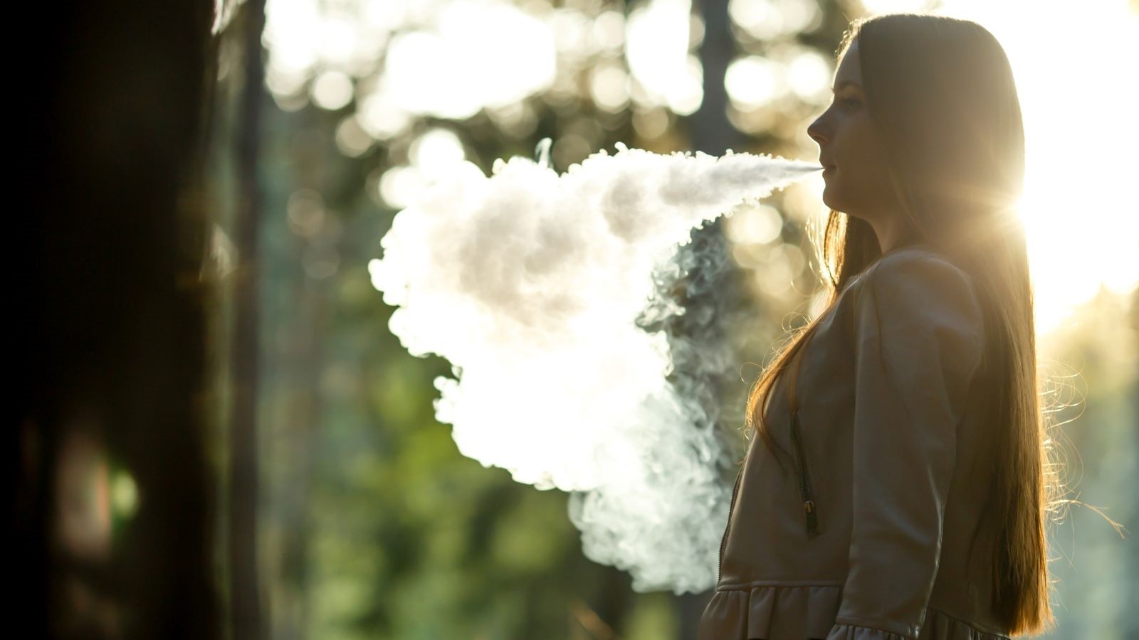 A youth blows out smoke from an electronic vaporizer