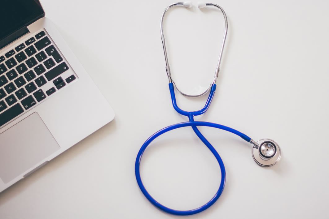A stethoscope sits next to an open laptop