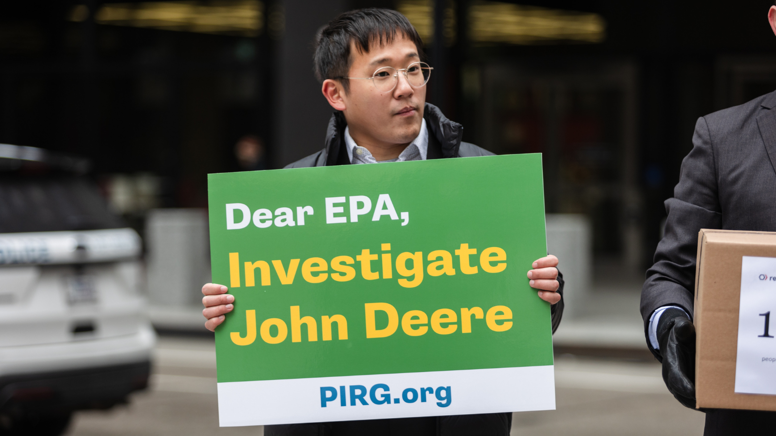 An advocate holds a green and yellow sign that says 