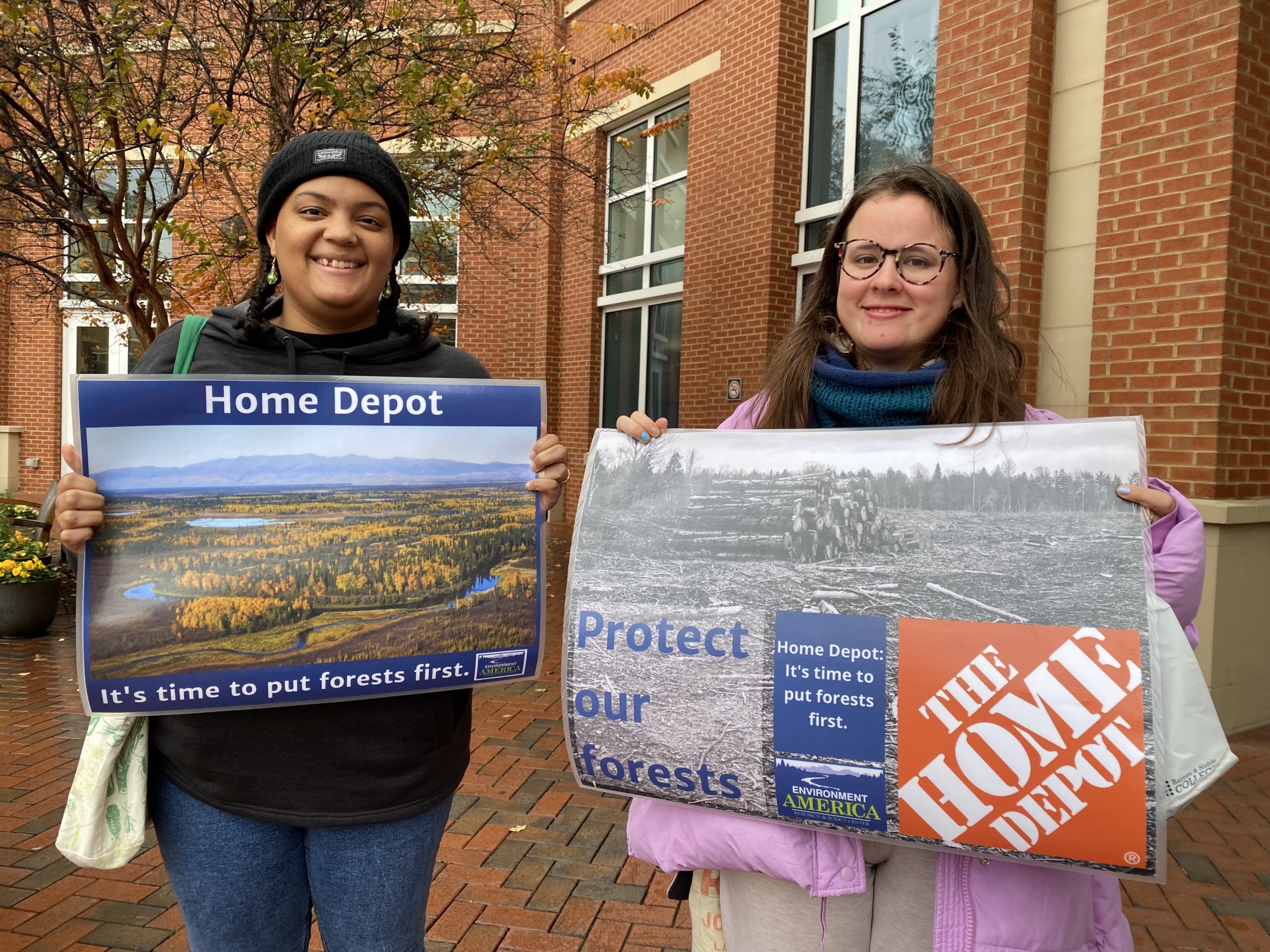 2 students hold signs calling on the home depot to put forests first