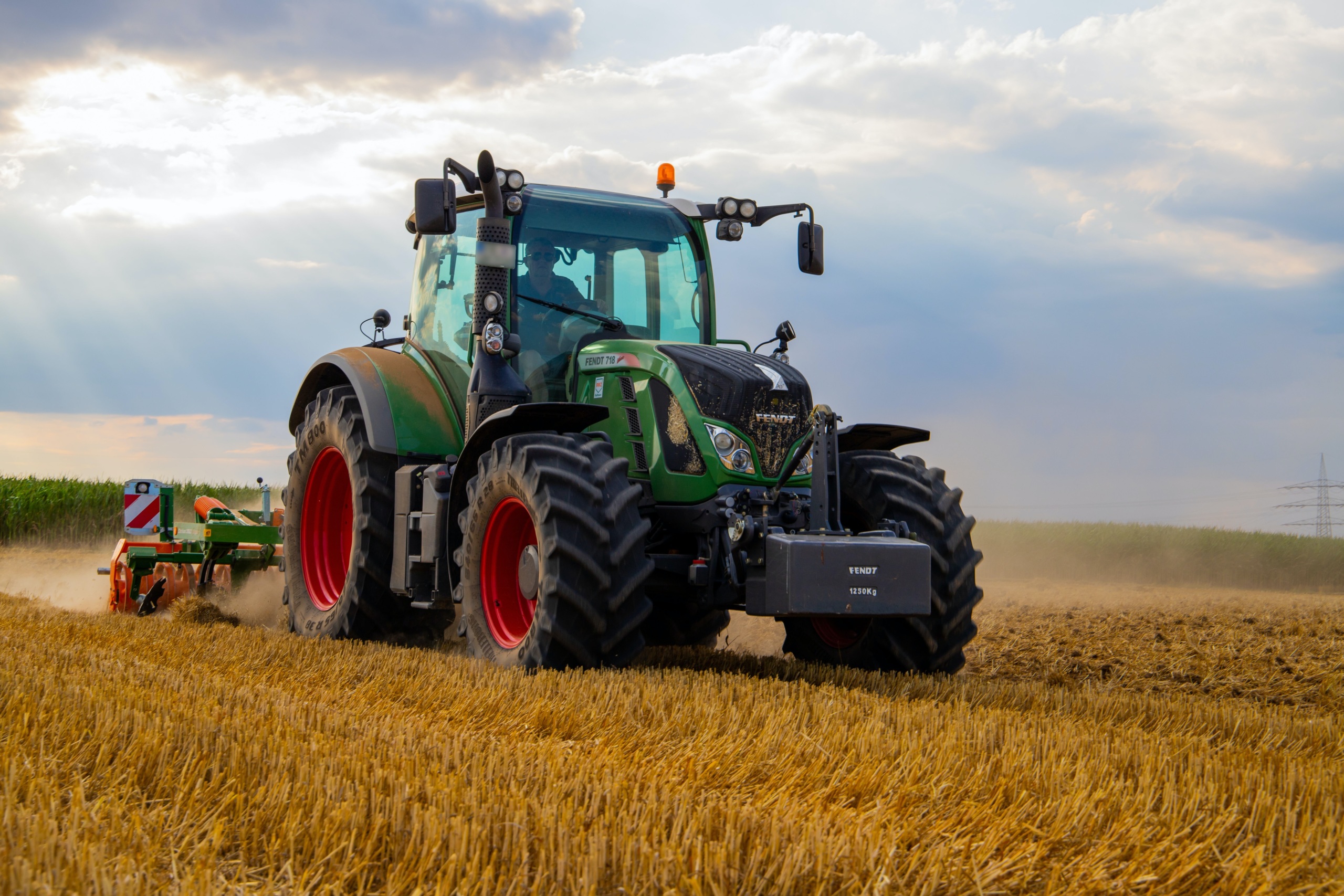 A green tractor drives through a field