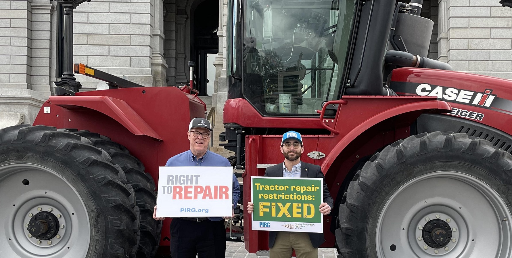 Repair.org's Willie Cade and Kevin O'Reilly from PIRG pose in front of the capitol with a tractor as part of the Right to Repair signing event.