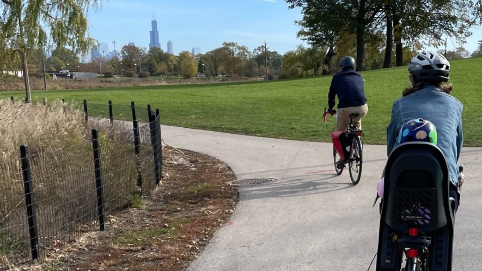 Family riding bikes on a path with Chicago skyline in the background
