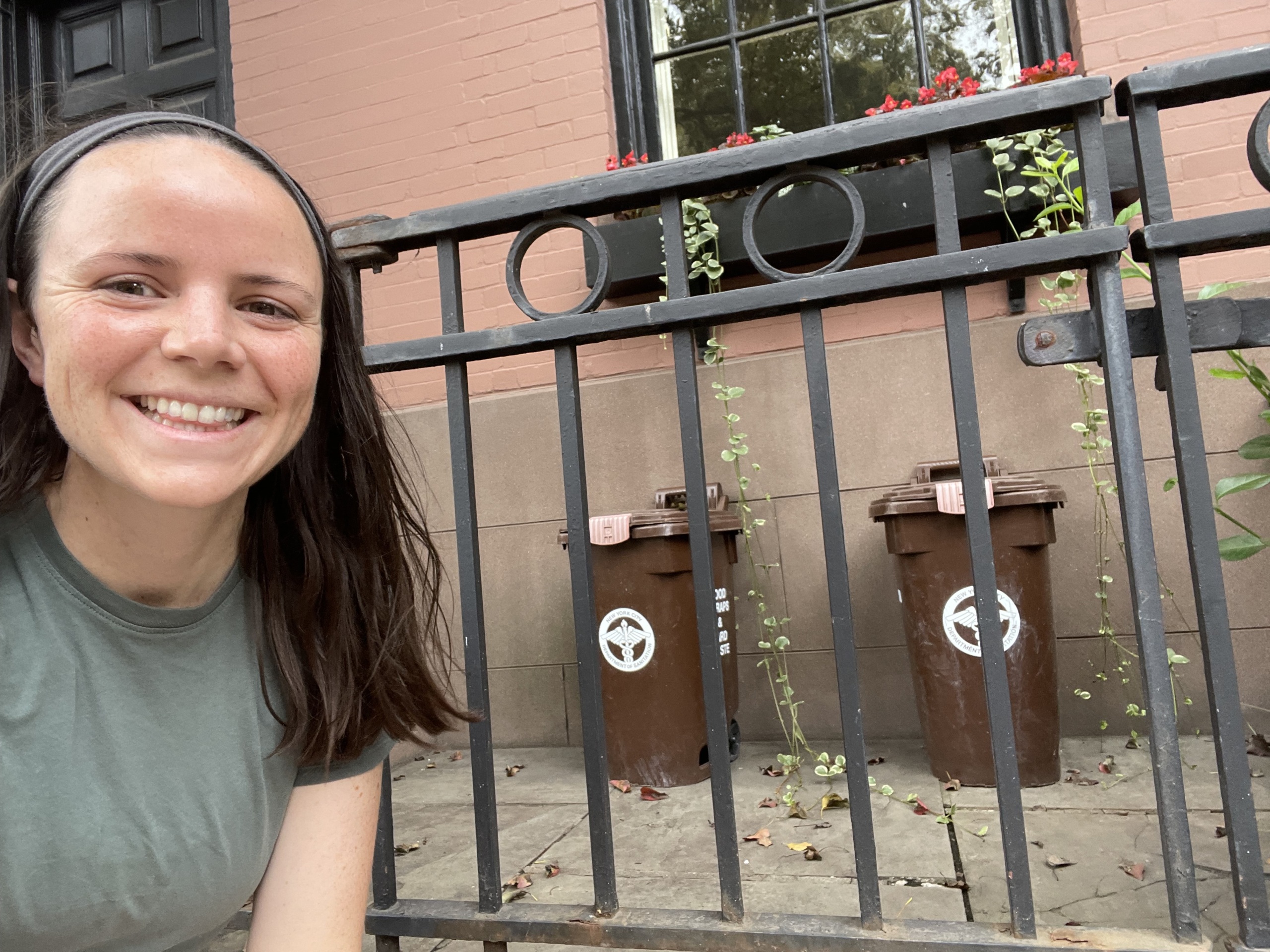 Danielle Melgar, Food & Agriculture Advocate, poses with organic waste collection bins in Brooklyn Heights