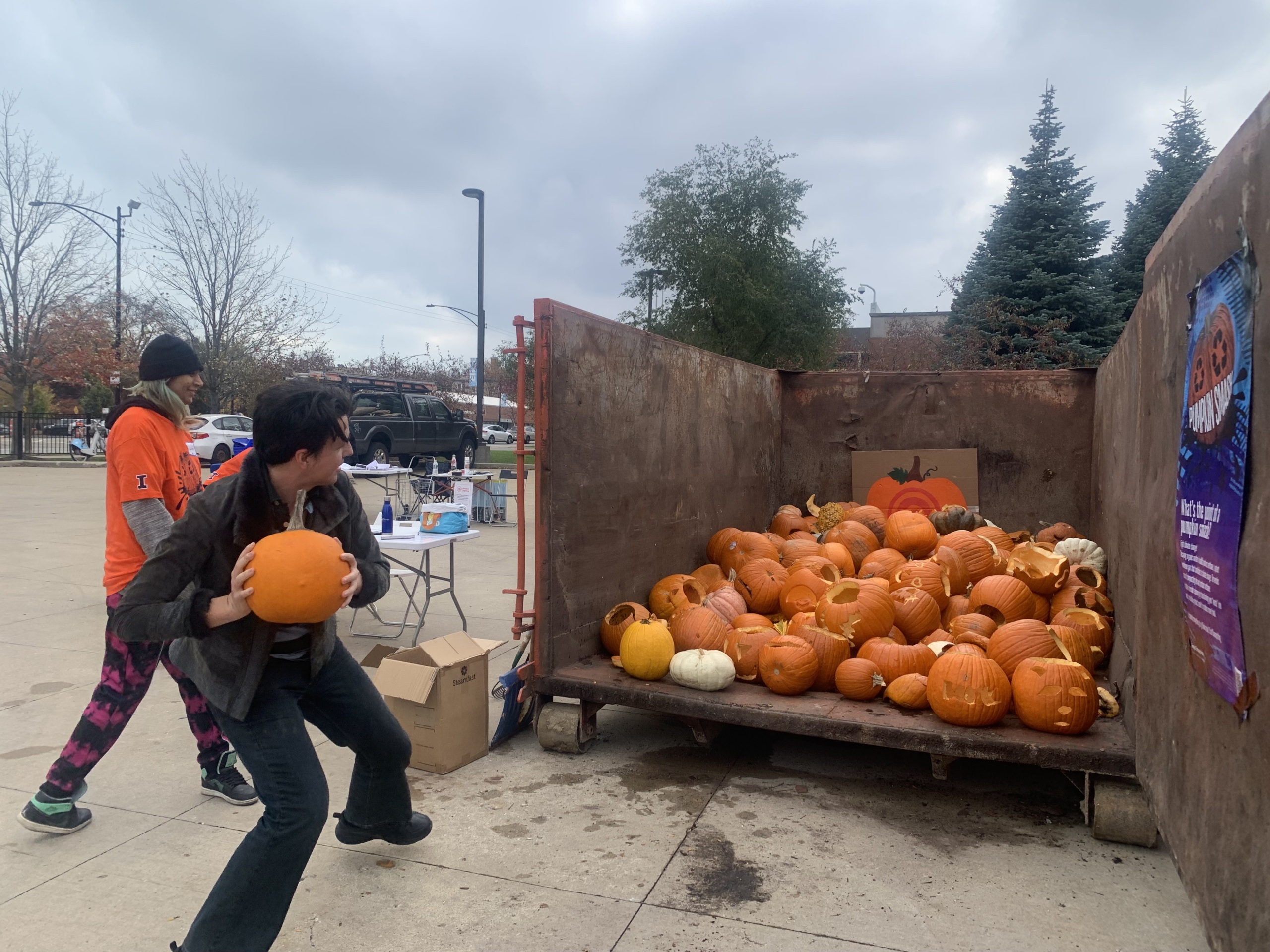 Throwing a pumpkin into a truck bed of pumpkins destined for compost