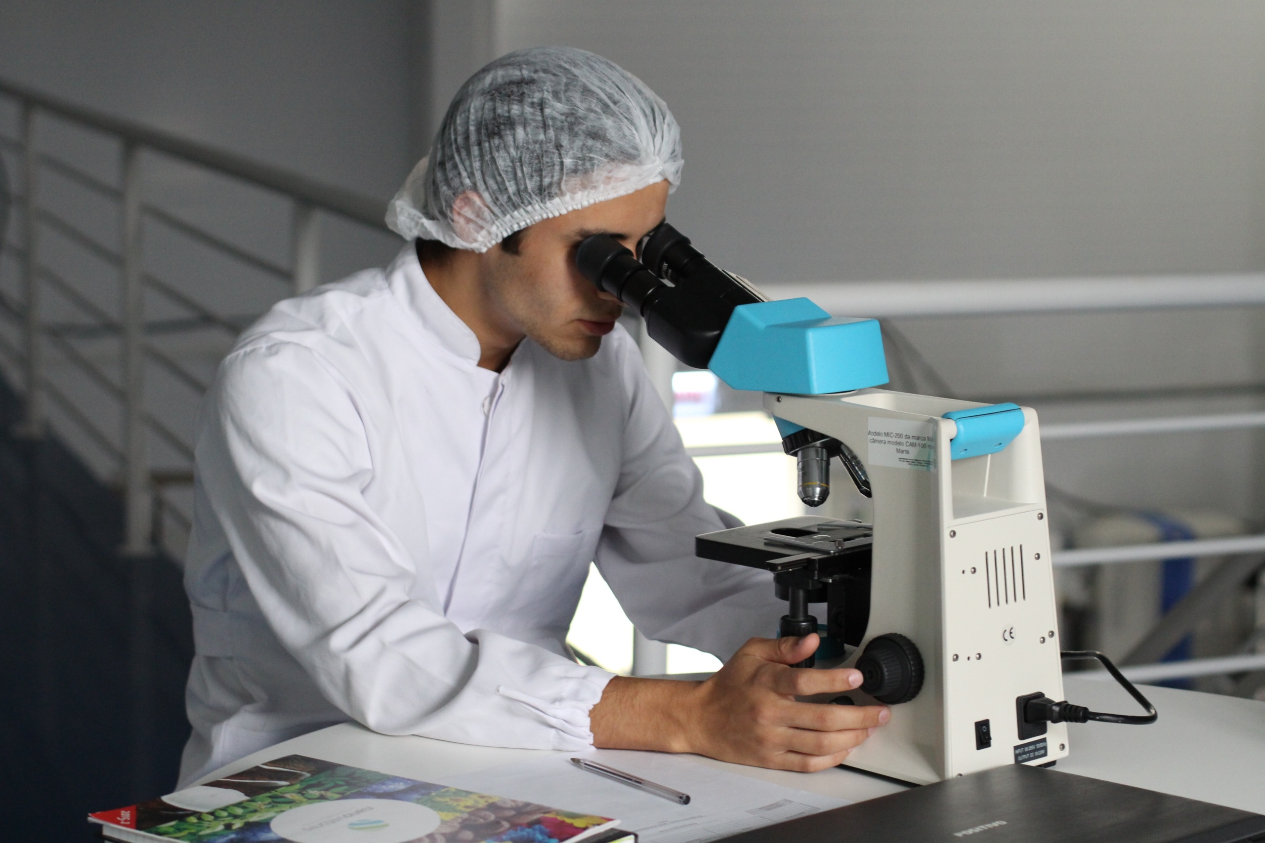 Scientist in lab coat looking through microscope