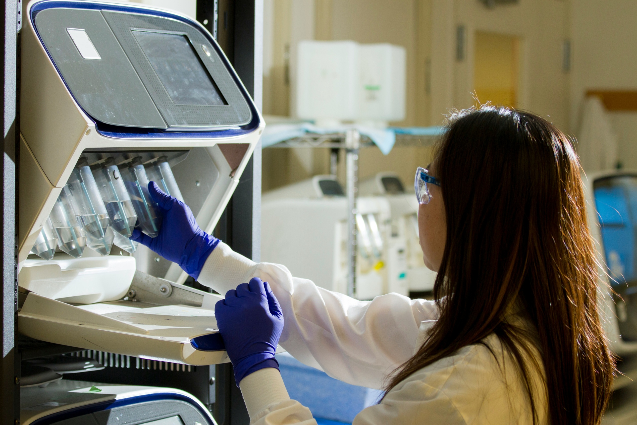 Woman in lab coat preparing lab test in front of a monitor