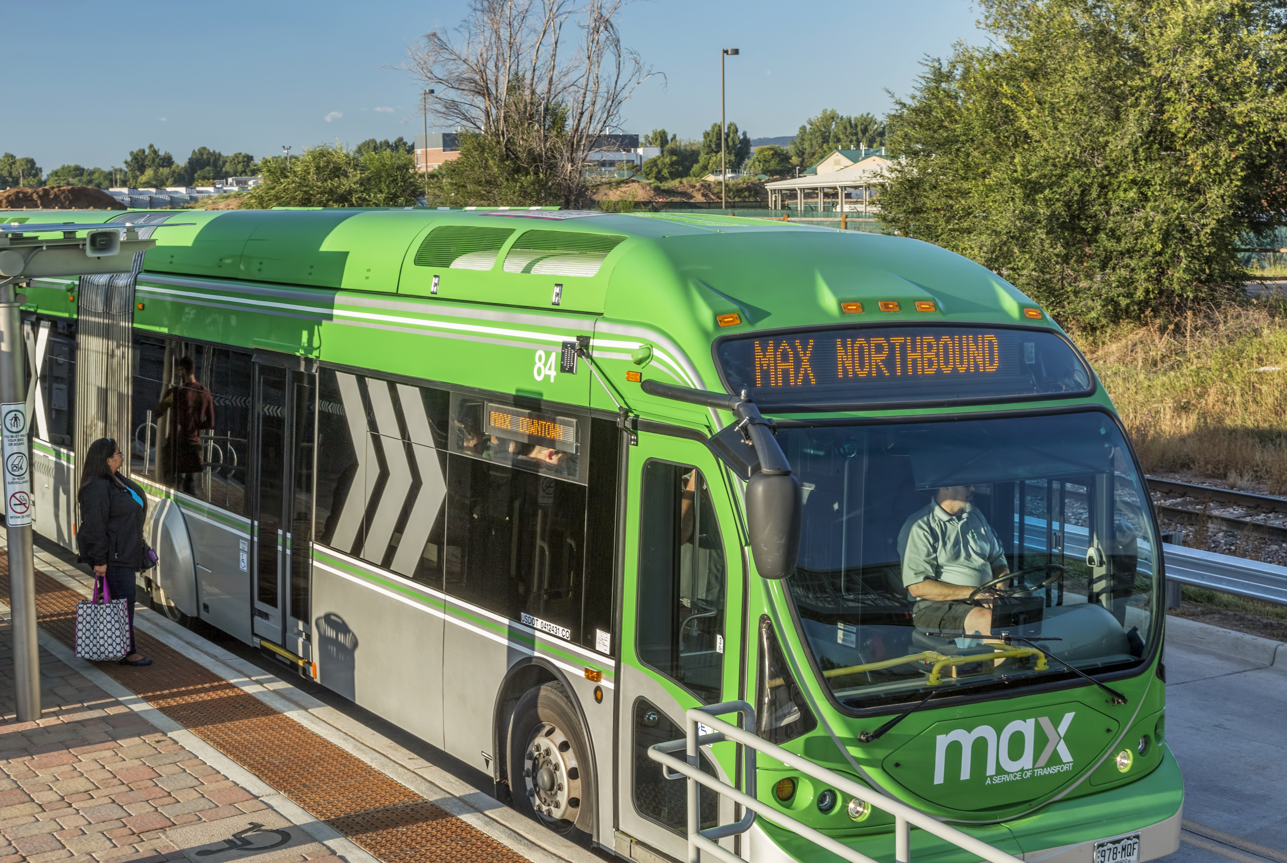 A green Fort Collins MAX Bus Rapid Transit bus at a stop.