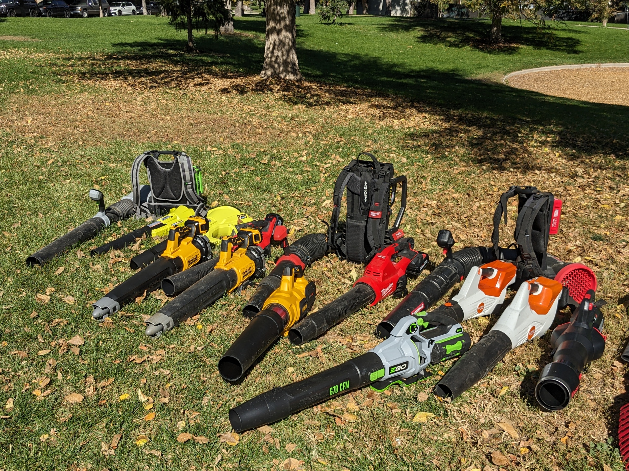 A display of electric leaf blowers from various brands in a park