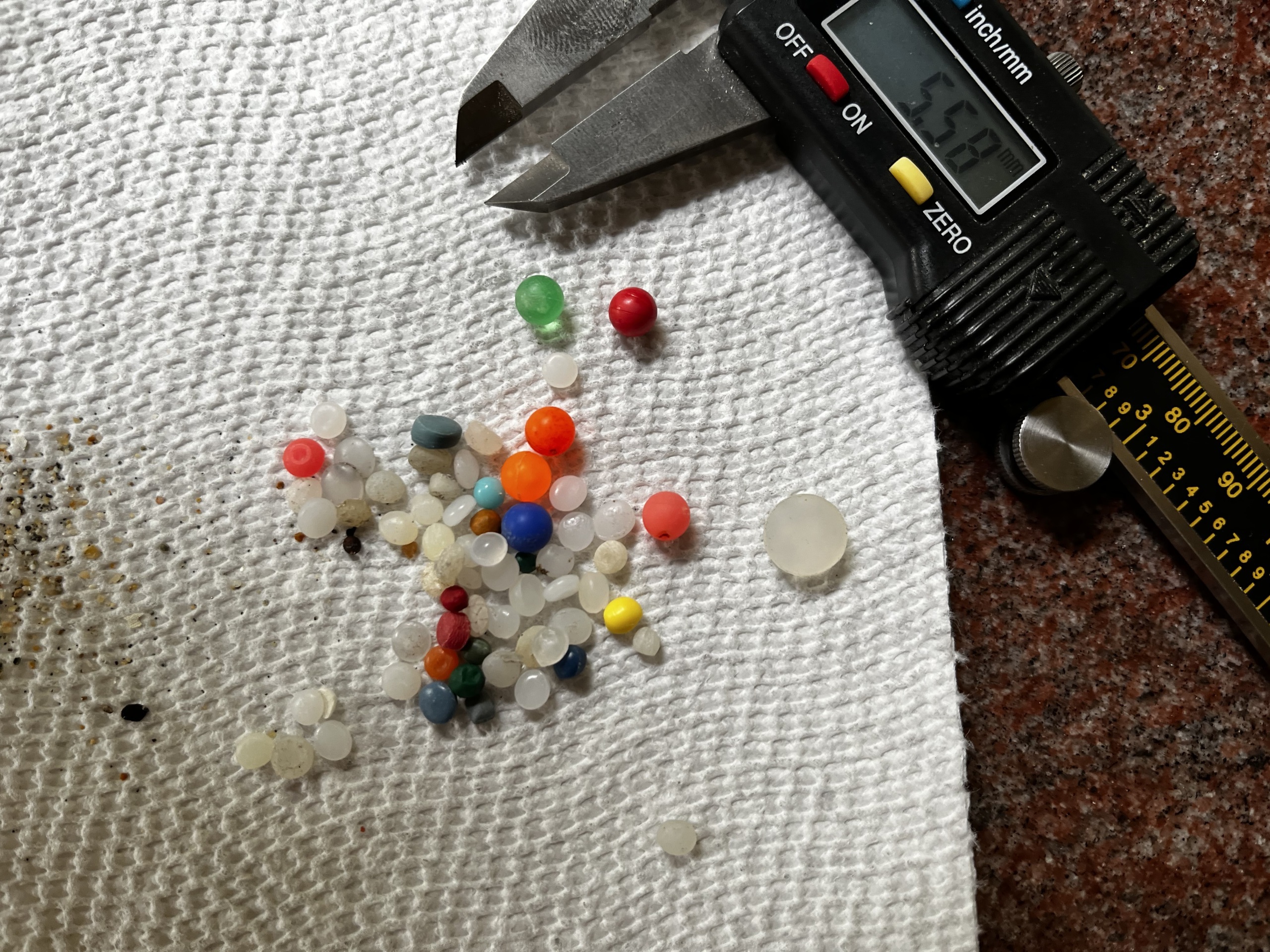 Photo of finds from the pellet hunt, including plastic pellets and other bits of plastic and a measuring device